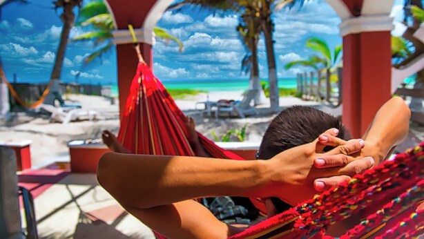 Un hamac sous un auvent rouge, avec vue sur la plage.