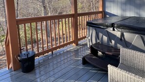 A covered outdoor deck with a grill, wicker furniture, and a view of trees. - Mountain View Modern Cottage in the Smokies W/ Hot Tub, Newly Renovated. (Sevierville)