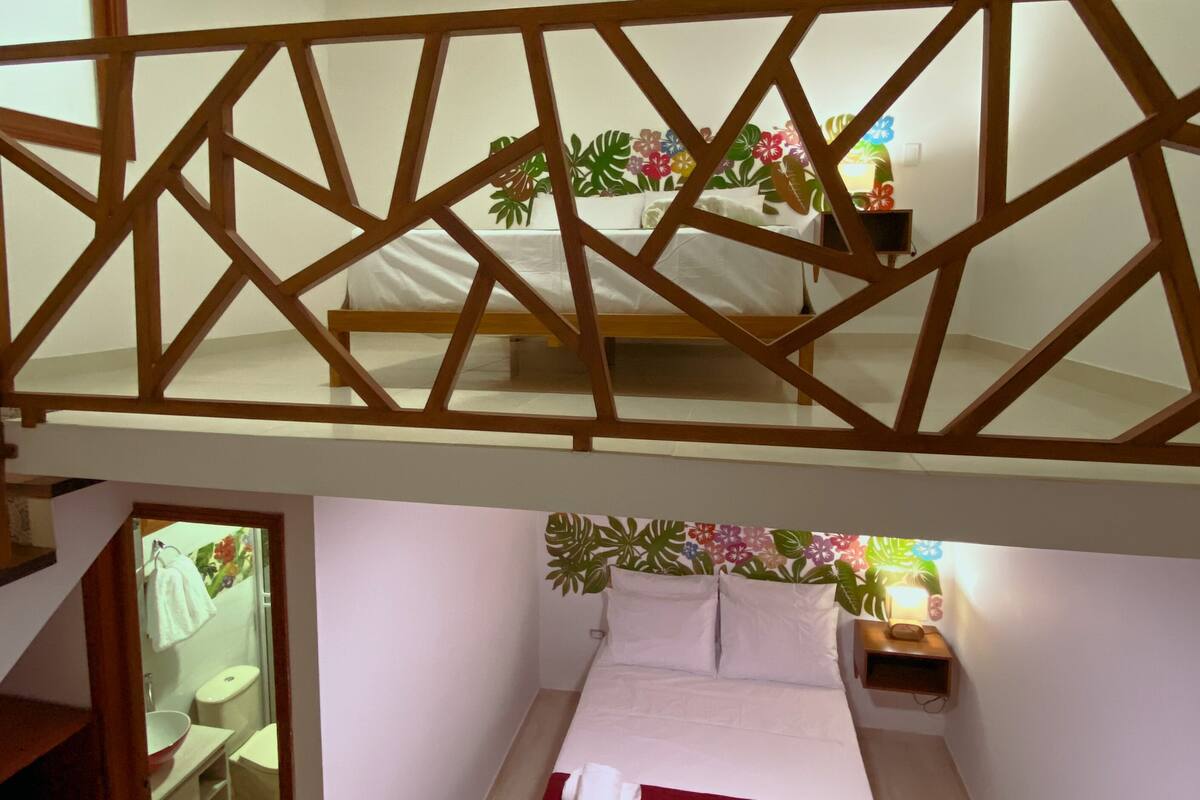 A bedroom with a bed, a wooden headboard, a nightstand, and a small shelf.