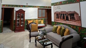 Un salón amplio con techo alto, un ventanal grande y un mural decorativo en la pared.