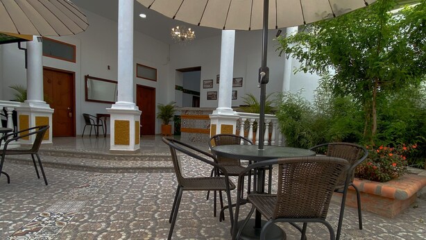 Un patio al aire libre con suelo de baldosas, muebles de mimbre y sombrillas que dan sombra.