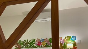 Una habitación con una cama, estructura de madera y un diseño floral en la pared.