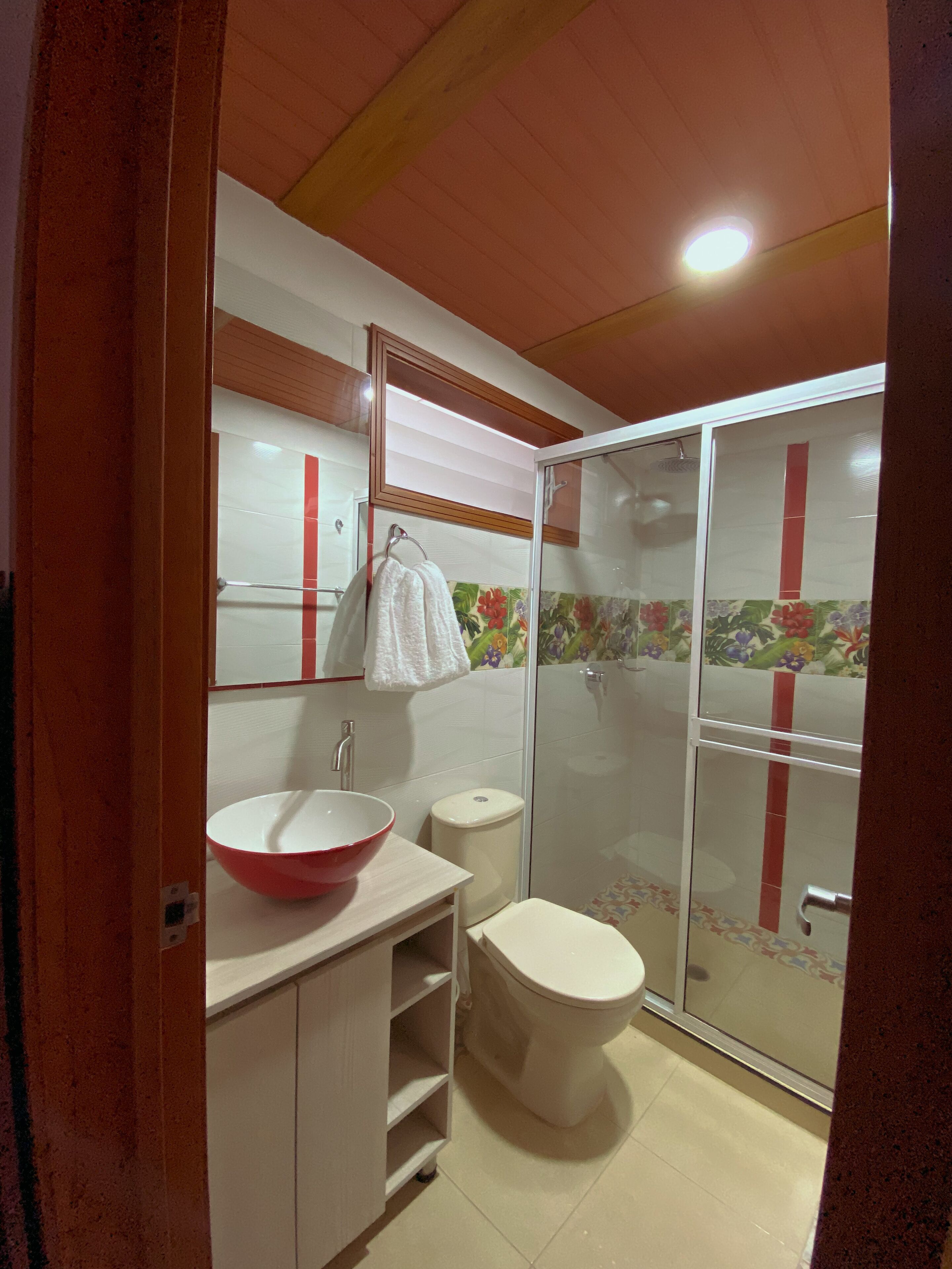 Un baño con lavamanos blanco, inodoro y cabina de ducha de cristal.