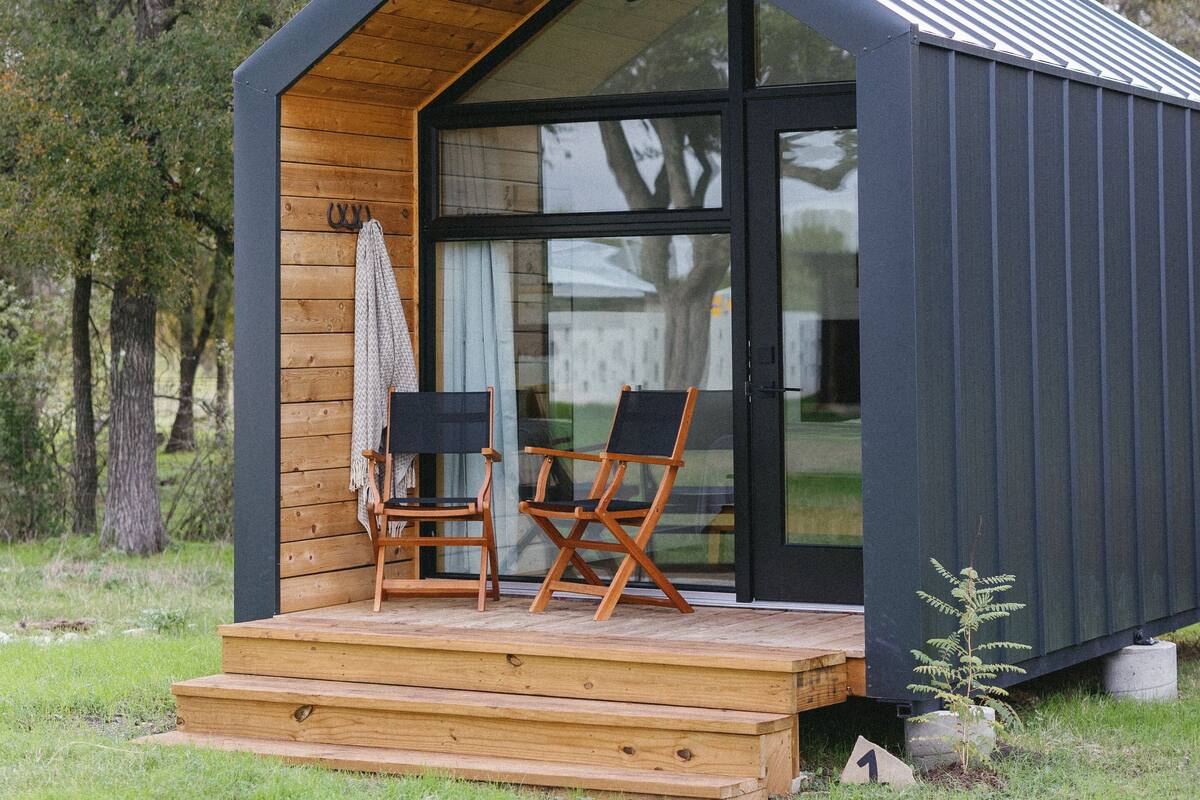 A modern cabin with a wooden deck and two chairs.
