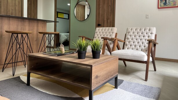 A modern living room with a wooden coffee table, two armchairs, and a small side table. - HOUSINN co-living Fátima (Medellín)