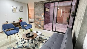 A modern living room with two blue armchairs, a sofa, a coffee table, and a patterned rug. - HOUSINN co-living Fátima (Medellín)