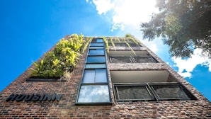 A brick building with a sign reading "Housinn" and a large window. - HOUSINN co-living Fátima (Medellín)