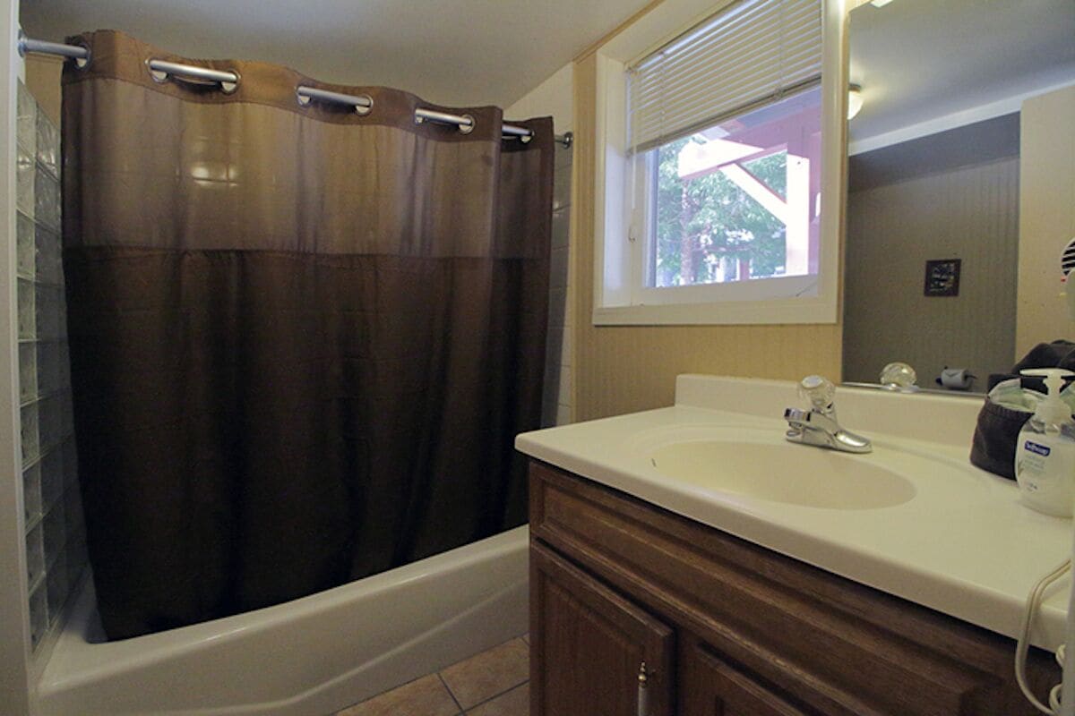 Une salle de bain avec une baignoire, un lavabo et une fenêtre avec des stores.