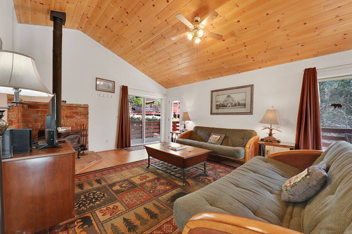 A cozy living room with a fireplace, a sofa, a coffee table, and a ceiling fan.
