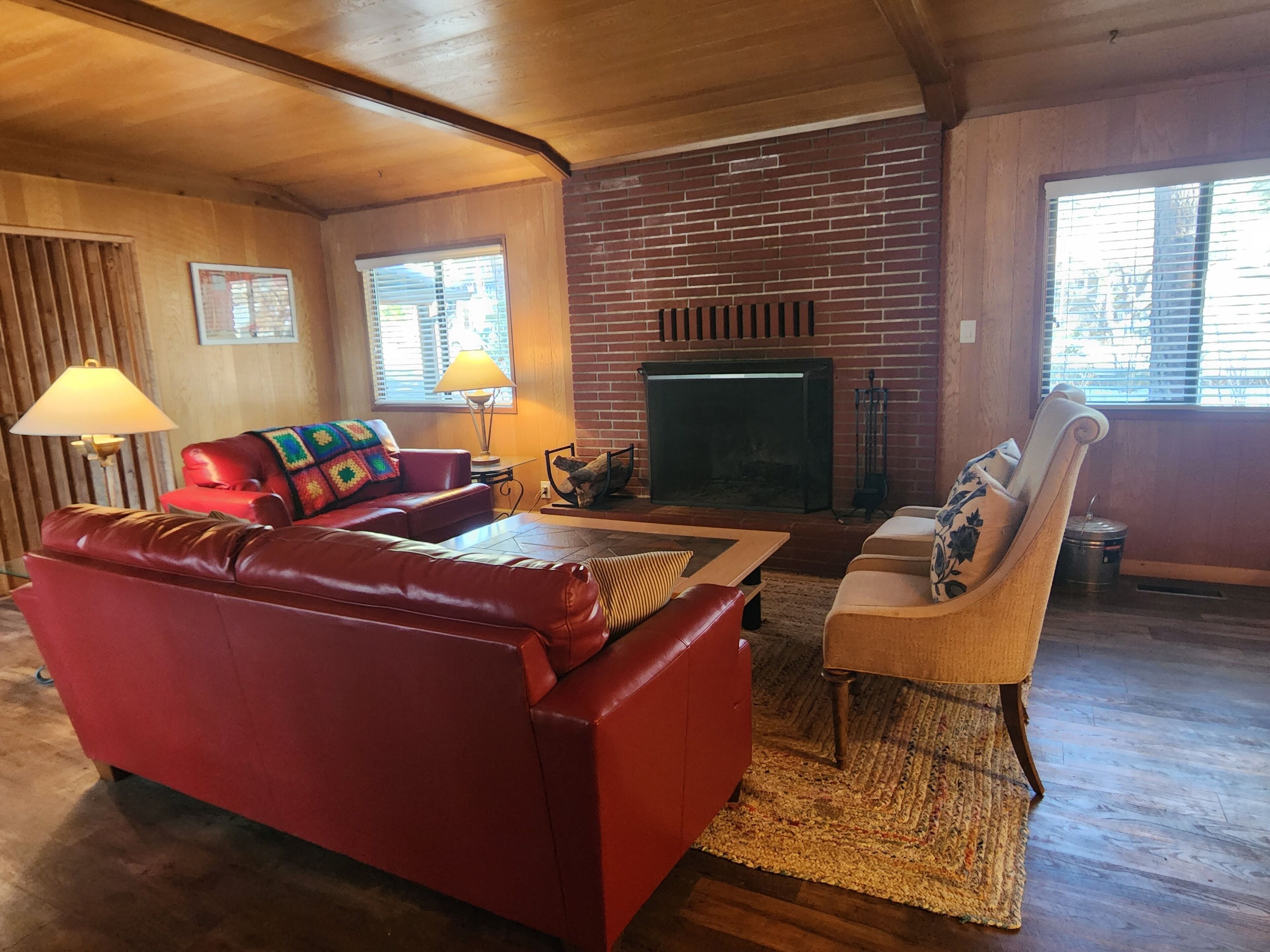 A living room with a red leather sofa, a patterned armchair, and a fireplace.
