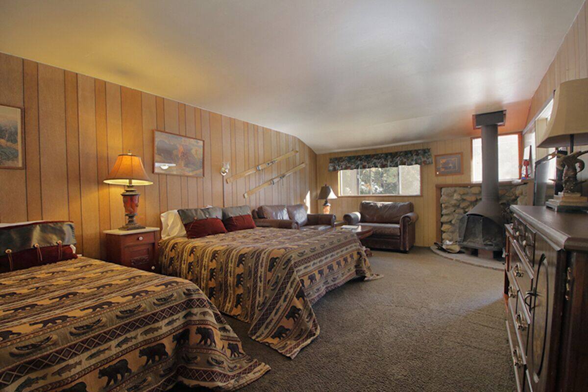 A cozy room with two beds, a fireplace, and a stone wall.