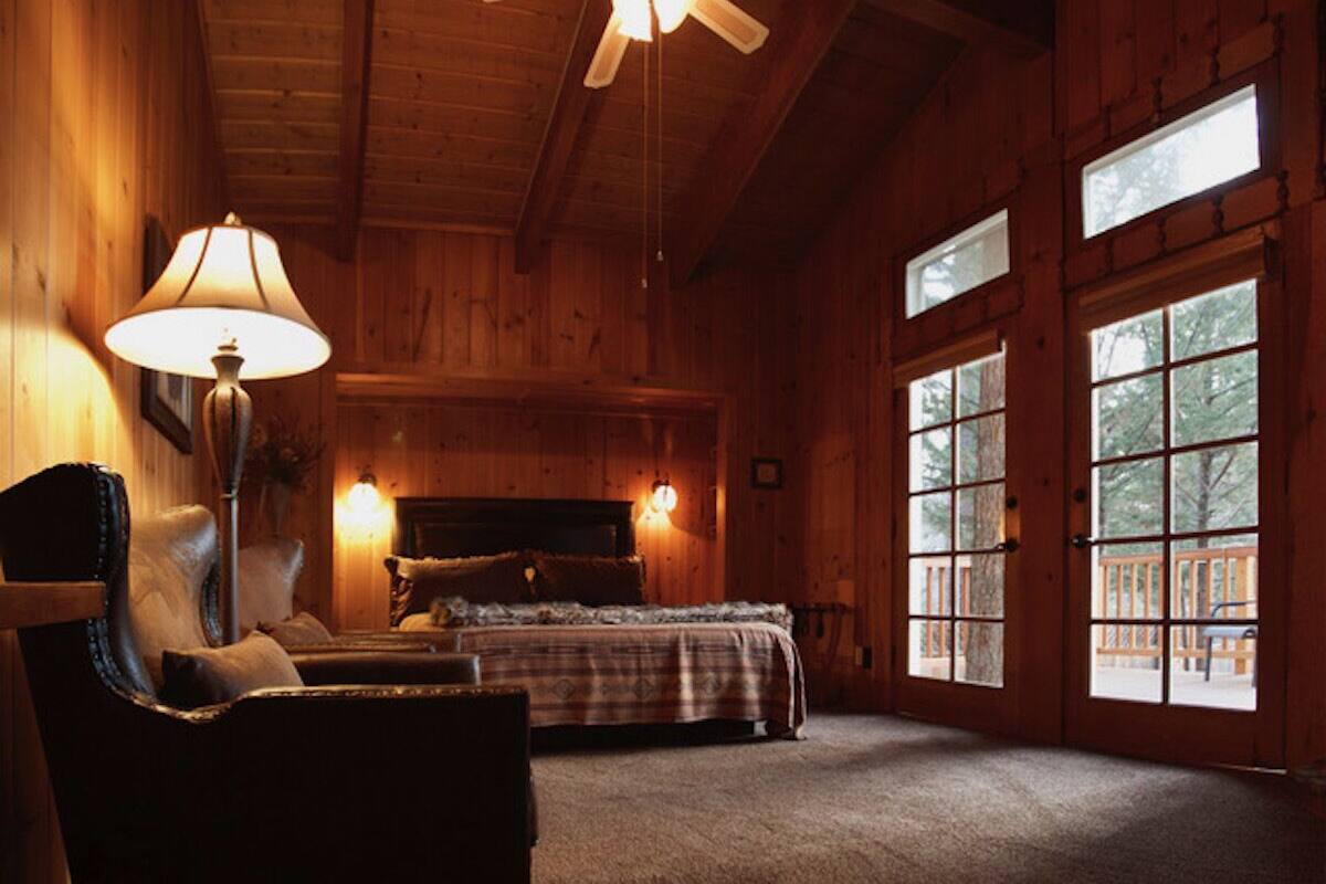 A cozy log cabin room with a bed, a chair, and a lamp.
