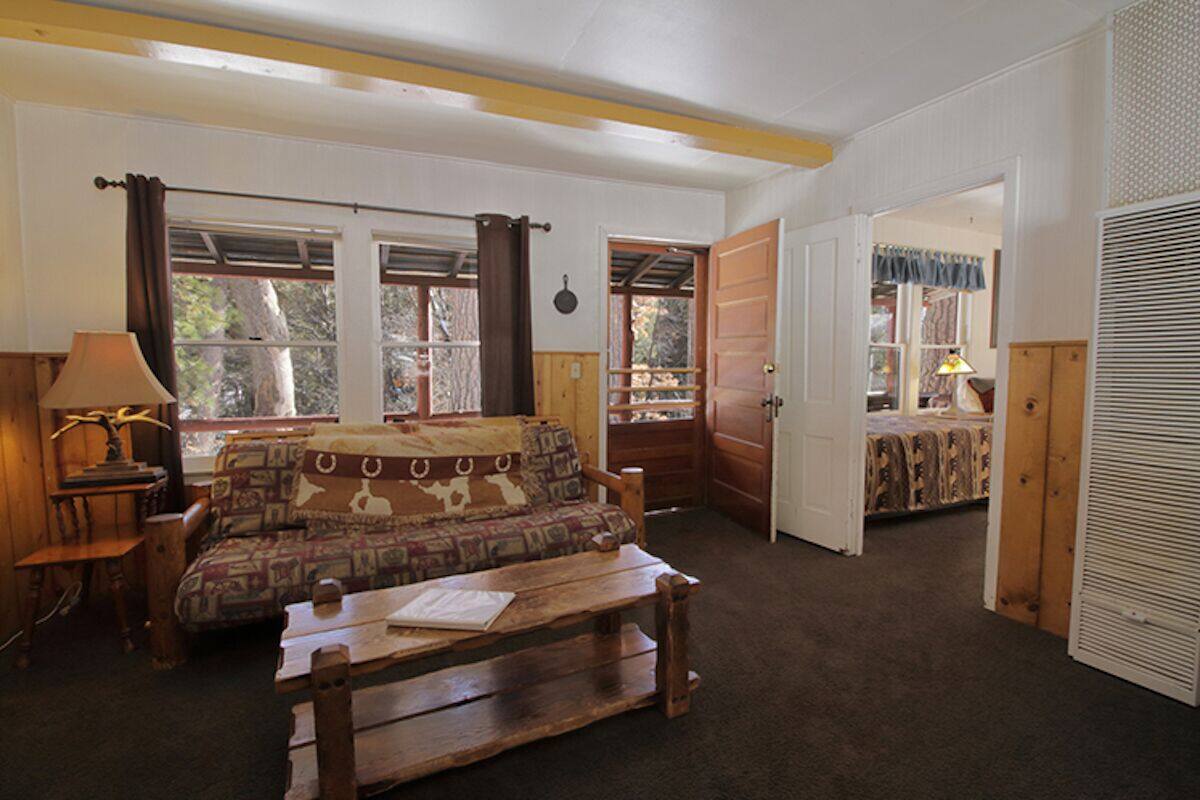 A cozy room with a bed, a wooden bench, a lamp, and a window with curtains.