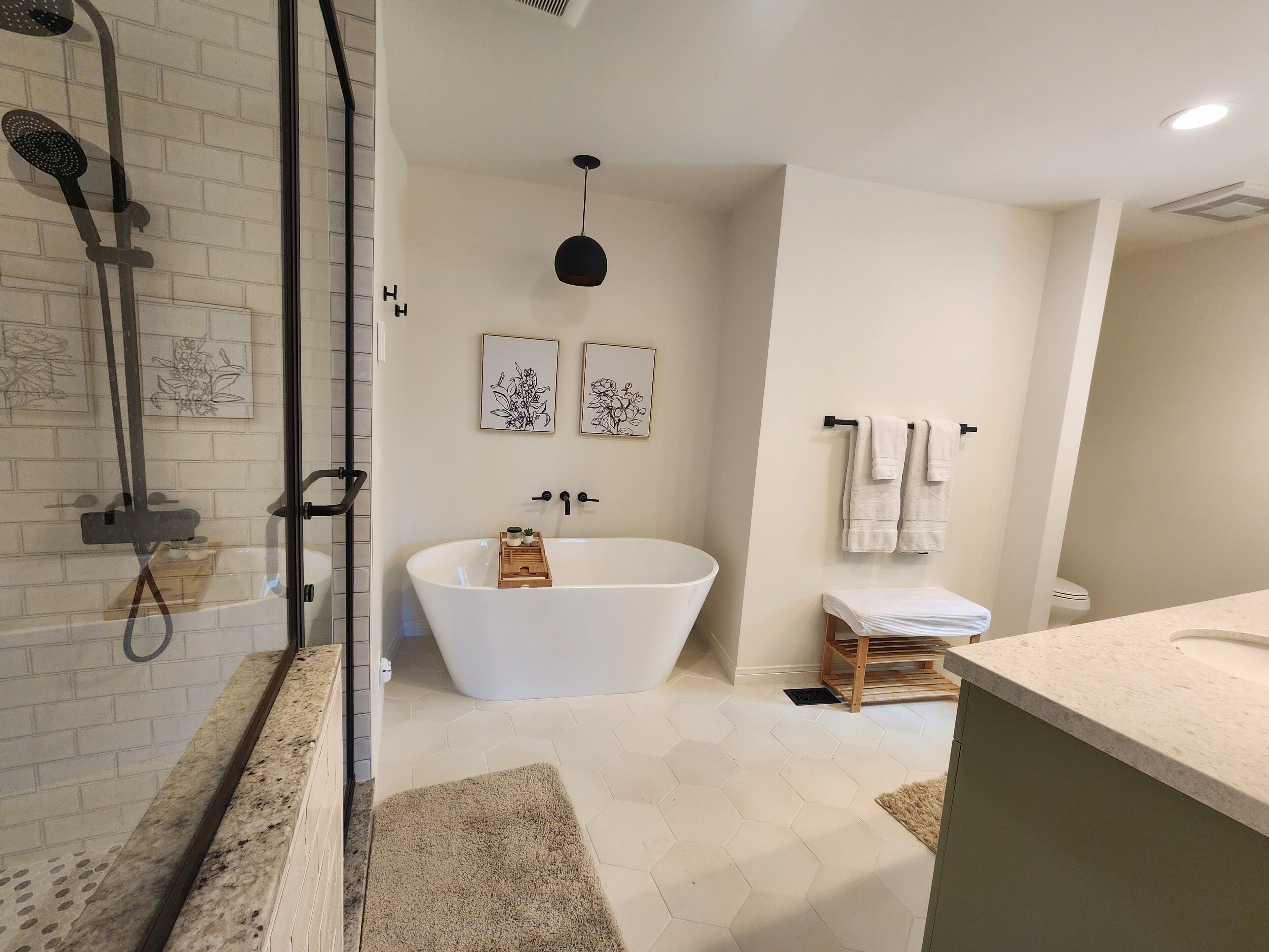 Ein modernes Badezimmer mit einer freistehenden Badewanne, einer Duschkabine aus Glas und einem Waschtisch mit Arbeitsplatte.