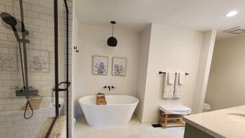 Ein modernes Badezimmer mit einer freistehenden Badewanne, einer Duschkabine aus Glas und einem Waschtisch mit Arbeitsplatte.