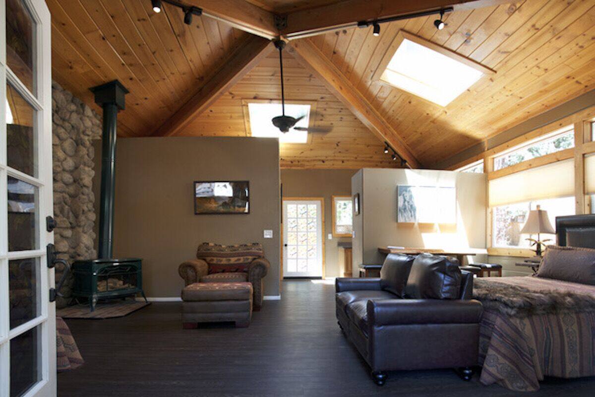 A spacious living room with a high ceiling, a fireplace, leather sofas, and a stone wall.