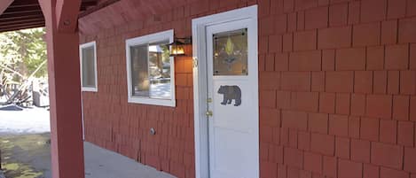 Un edificio de ladrillo con una puerta blanca, una ventana pequeña y una decoración de oso en la puerta.