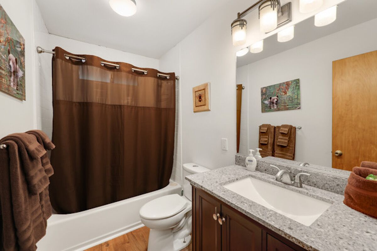 Une salle de bain avec une baignoire, des toilettes, un lavabo et des meubles en bois.