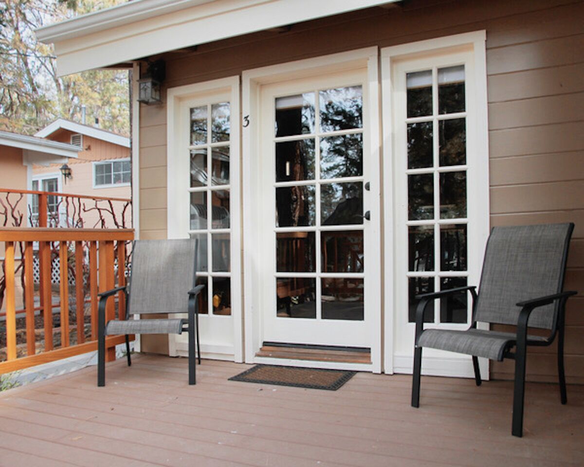 Une véranda avec deux chaises et une balustrade en bois.