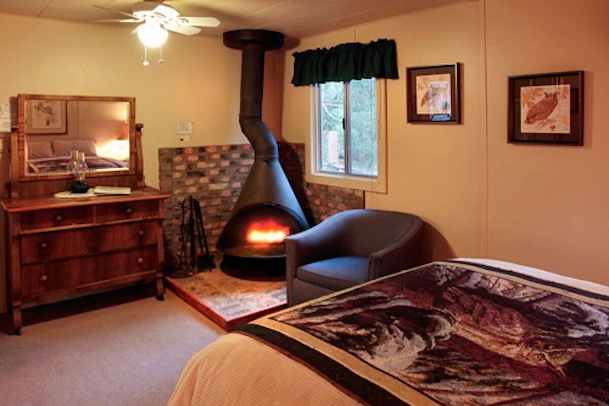 A cozy room with a fireplace, a dresser, a chair, and a bed with a patterned bedspread.