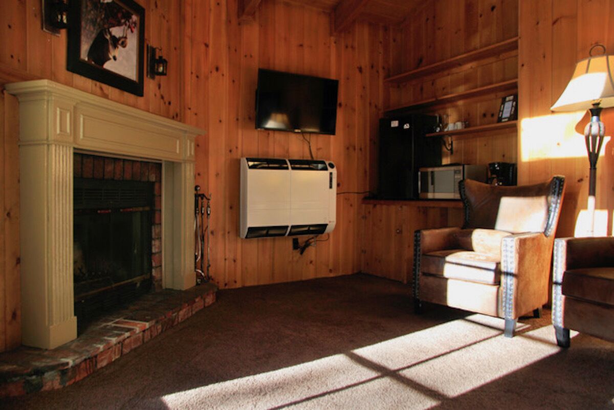 A cozy room with a fireplace, a television, a microwave, and a chair.