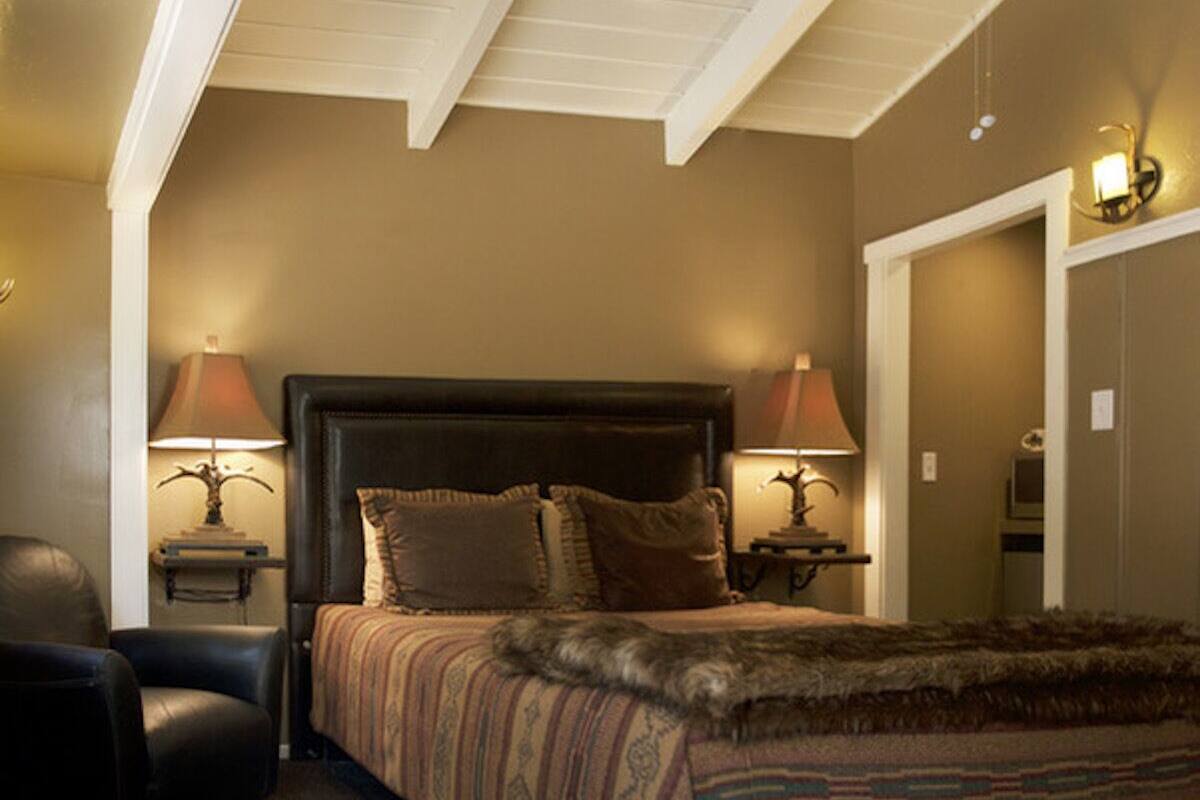 A bedroom with a large bed, two bedside lamps, a chair, and a door.