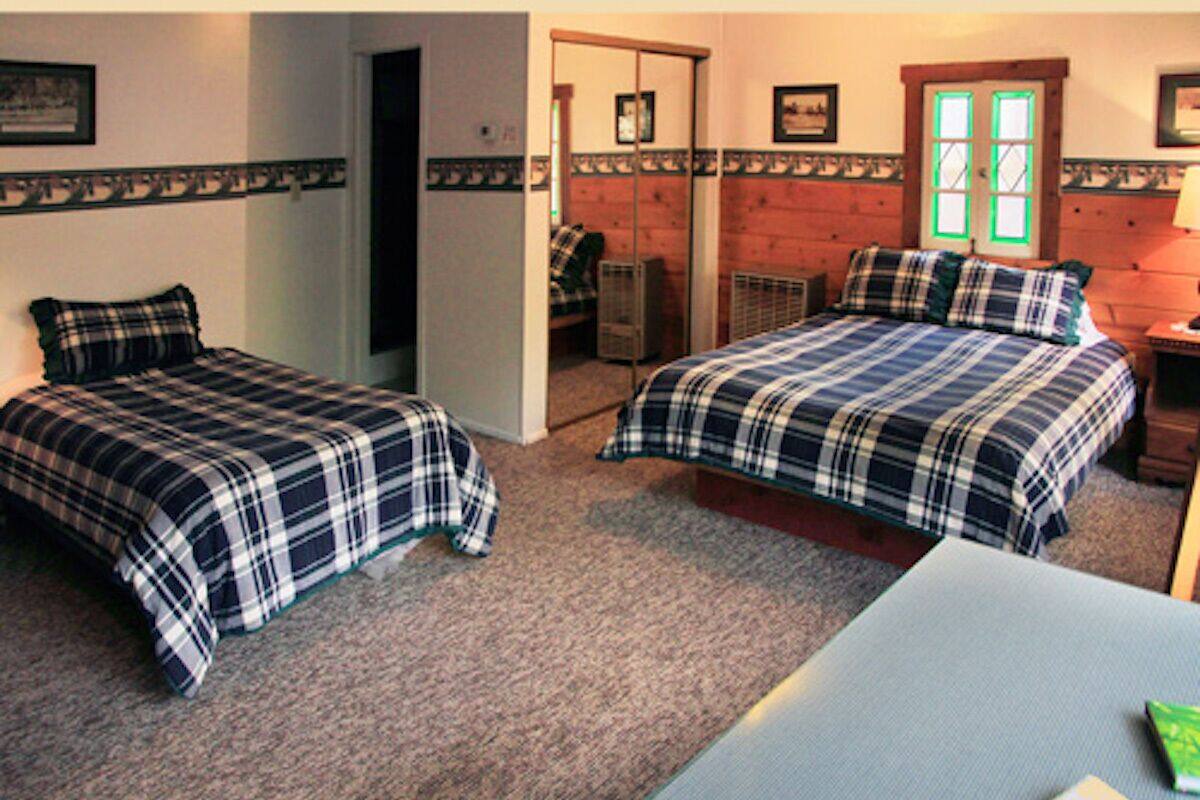 A room with two beds, a wooden door, and a small table.