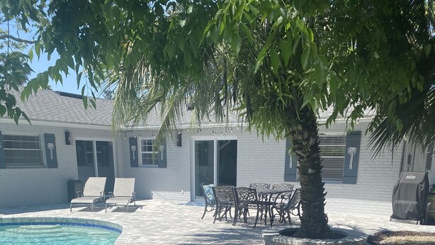 A swimming pool with a curved edge, surrounded by a paved patio with lounge chairs and a table. - Pool Home near Ponte Vedra Beach! (Ponte Vedra Beach)