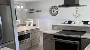 A modern kitchen with a marble countertop, stainless steel appliances, and a clock on the wall. - Pool Home near Ponte Vedra Beach! (Ponte Vedra Beach)