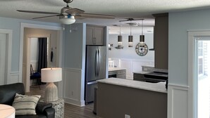 A modern kitchen with a refrigerator, a dining area, and a living room with a sofa and lamp. - Pool Home near Ponte Vedra Beach! (Ponte Vedra Beach)