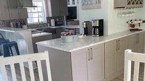A modern kitchen with a central island, white cabinetry, and a dining area with a dark wooden table and white chairs. - Pool Home near Ponte Vedra Beach! (Ponte Vedra Beach)