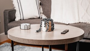 Ein runder Couchtisch mit weißer Marmorplatte, schwarzen Metallbeinen und einem grauen Teppich mit Muster darunter.