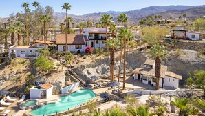 A resort with multiple buildings, a swimming pool, and palm trees.