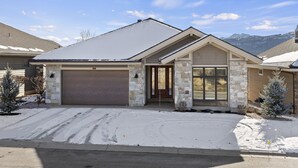 A residential house with a garage, stone facade, and a snowy driveway.