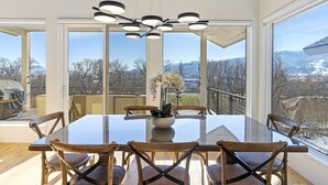 A dining area with a glass table, wooden chairs, and a modern chandelier.