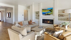 A modern living room with a sofa set, a coffee table, a fireplace, and a TV mounted on the wall.