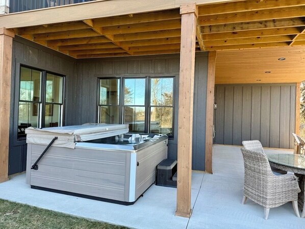 A hot tub under a wooden pergola with a glass table and wicker chairs. - Cliffside Cottage, Private Pond, 50 acres w/ Breathtaking views near Galena, IL (Elizabeth)