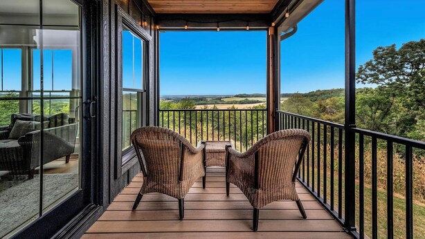 A balcony with wicker chairs and a table, overlooking a scenic landscape. - Cliffside Cottage, Private Pond, 50 acres w/ Breathtaking views near Galena, IL (Elizabeth)