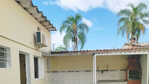Un patio con césped artificial, una mesa blanca con sillas y un horno de ladrillo.