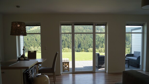 A spacious living area with a large sliding glass door leading to a patio with a view of a forested area. - Apartment Ritzhagen **** (Willingen (Upland))