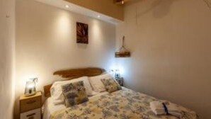 Une chambre à coucher comprenant un lit, des tables de chevet, un ventilateur de plafond et un luminaire fixé au mur.