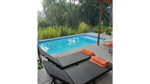 A poolside area with a pool, lounge chairs, and a wooden deck. - Rouana Guest Farm (Stellenbosch)