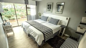 A bedroom with a large bed, a small bedside table, a chair, and a view of the outdoors. - Rouana Guest Farm (Stellenbosch)