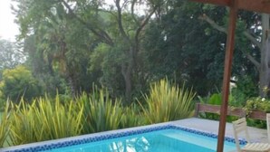 A poolside area with a pool, lounge chairs, and a wooden deck. - Rouana Guest Farm (Stellenbosch)