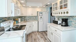 A modern kitchen with white cabinetry, a black stove, and a built-in refrigerator. - Anchorage 404 (Siesta Key)