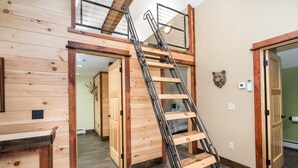 Un dormitorio estilo loft con escalera de madera y cama en altillo.