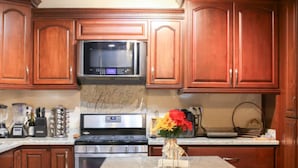 A kitchen with wooden cabinets, a granite countertop, a microwave, a stove, and a ceiling fan. - Dive into the relaxed elegance of our 4-bedroom haven in Zona Dorada, Mexicali's prestigious district, combining comfort, security, and luxury. Ideally nested near bustling plazas, trendy restaurants, and lively casinos, our property is perfect (Mexicali)
