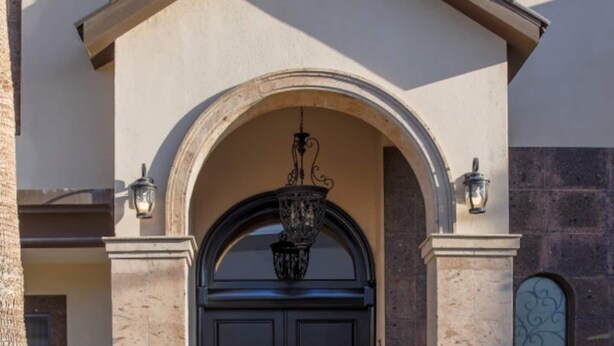 A building with a large arched entrance, a black door, and a hanging light fixture. - Dive into the relaxed elegance of our 4-bedroom haven in Zona Dorada, Mexicali's prestigious district, combining comfort, security, and luxury. Ideally nested near bustling plazas, trendy restaurants, and lively casinos, our property is perfect (Mexicali)