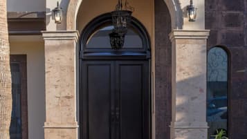 Un bâtiment doté d’une grande entrée en arc de cercle, d’une porte noire et d’un luminaire suspendu.