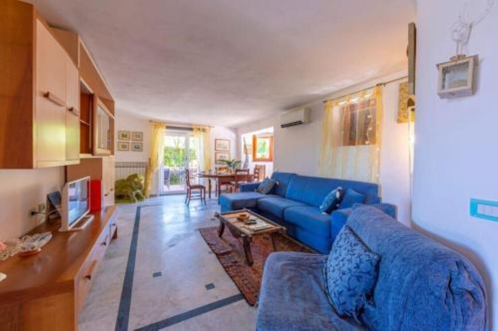 A living room with a blue sofa, a coffee table, and a TV on a wooden cabinet.